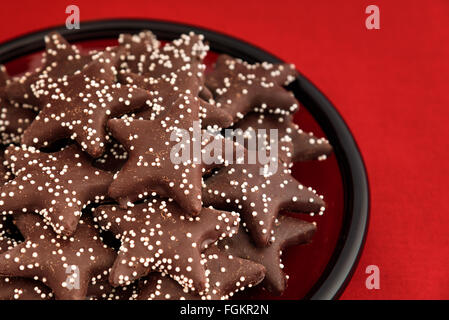 A forma di stella ricoperta di cioccolato i cookie su una targhetta rossa Foto Stock