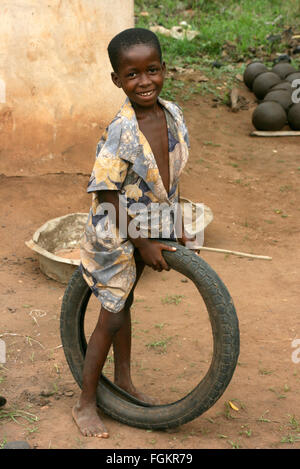 Sorridente ragazzo africano rotoli stick e pneumatico in Benin, Africa occidentale. Foto Stock