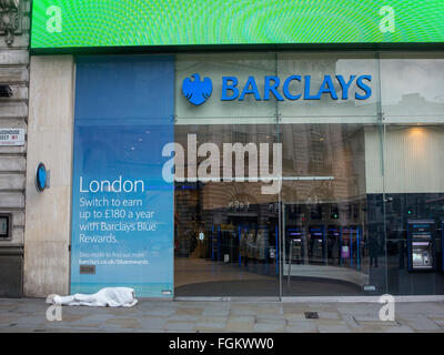 Un netto contrasto tra una persona senza dimora dormono per strada e una banca internazionale di Londra Foto Stock