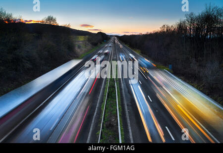 Sentieri di luce del veloce movimento di vetture su autostrada trafficata al crepuscolo Foto Stock