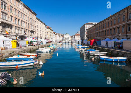 Gli edifici si riflette nelle calme acque del mare del Canal Grande nella città di Trieste, Italia. Chiesa di San Antonio sullo sfondo Foto Stock