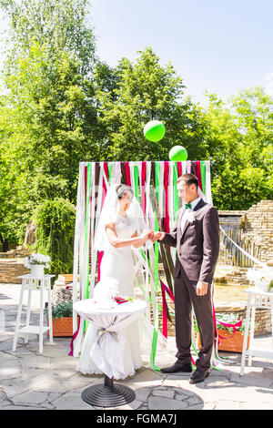Ritratto di sposa felice mettendo golden ring su stallieri mano alla cerimonia di nozze Foto Stock