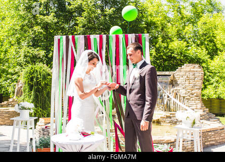 Ritratto di sposa felice mettendo golden ring su stallieri mano alla cerimonia di nozze Foto Stock