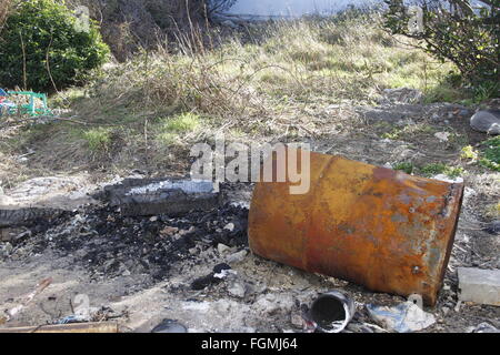 Rusty, vecchio barile di petrolio inceneritore con i contenuti suddivisi in giardino Foto Stock