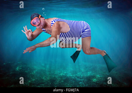 Uomo in costume da bagno retrò nuota sott'acqua in mare Foto Stock