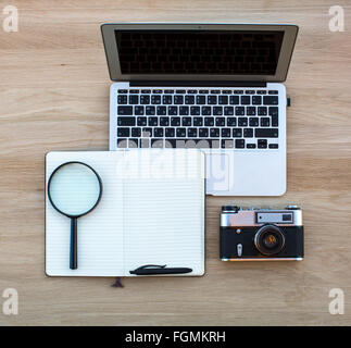 Notebook, blocco note con penna, Magnifier e la fotocamera è disposto su una superficie di legno. Foto Stock