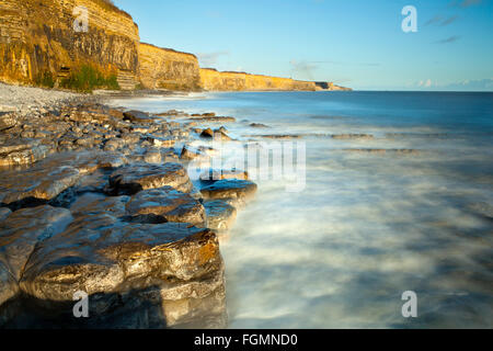 Guardando verso est da St Donats, Vale of Glamorgan ad alta marea, poco prima del tramonto di una lunga esposizione, sfocatura del mare. Foto Stock