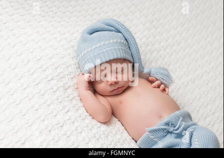 Nove giorni di età, neonato ragazzo indossa una maglia, piccolo uomo tuta  con cappuccio newsboy e papillon. Egli dorme in una piccola sedia con un  pugno sotto il suo Foto stock 