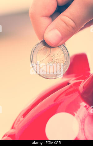 Bambino gettato in Piggy coin - due euro Foto Stock