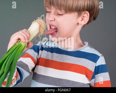 Funny kid tenendo il porro vegetale, rifiuta di mangiare Foto Stock