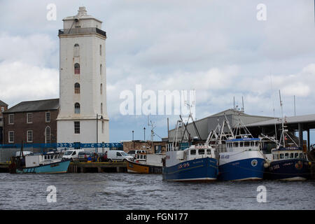 Barche da pesca presso il North Shields Fish Quay nel nord-est dell'Inghilterra. La bassa torre faro si affaccia sul porto. Foto Stock