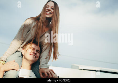 Ritratto di donna felice seduta sull uomo di spalle contro il cielo. Tonica con colori Vintage. Messa a fuoco selettiva. Foto Stock