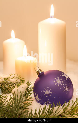 Viola palla di Natale con ornamenti e con candele di accensione sulla neve Foto Stock