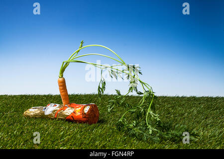 coniglietto pasquale al cioccolato pugnalato con una carota Foto Stock