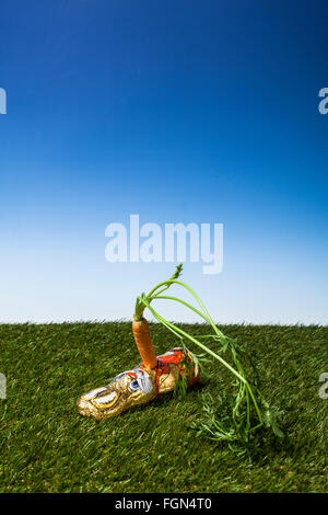 coniglietto pasquale al cioccolato pugnalato con una carota Foto Stock