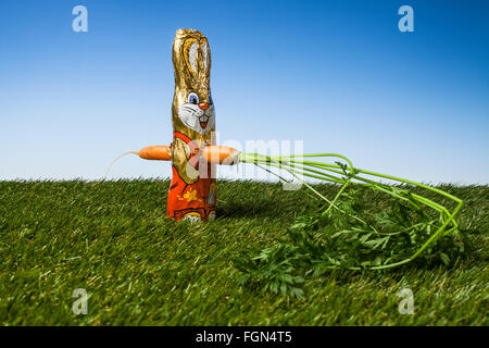coniglietto pasquale al cioccolato pugnalato con una carota Foto Stock