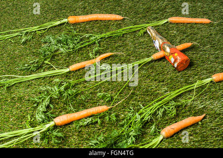 coniglietto pasquale al cioccolato pugnalato con una carota Foto Stock