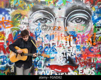 Giovane uomo di suonare una chitarra nella parte anteriore della parete di Lennon a Praga, Repubblica Ceca Foto Stock