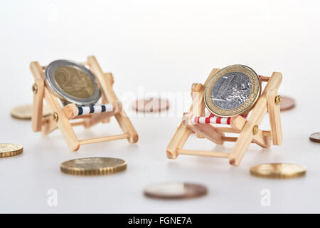 Concetto shot per risparmi vacanze con le monete in euro che giace sulla sdraio in miniatura isolati su sfondo bianco Foto Stock