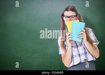 Immagine composita di geeky hipster nasconde il suo volto dietro il blocco note Foto Stock