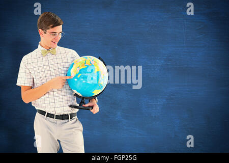 Immagine composita di geeky hipster tenendo un globo sorridente in telecamera Foto Stock