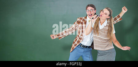 Immagine composita di felice geeky hipsters cantando con microfono Foto Stock