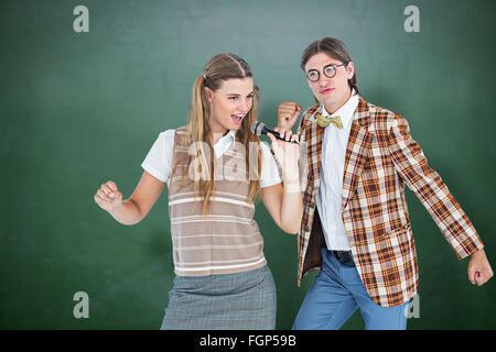 Immagine composita di felice geeky hipsters cantando con microfono Foto Stock