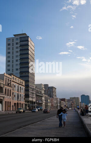 La vita quotidiana a Cuba - Giovane camminando sotto braccio lungo la El Malecon, Havana, Cuba, West Indies, dei Caraibi e America centrale Foto Stock