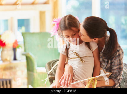 Madre baciare la figlia sua guancia Foto Stock