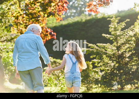 Nonna e nipote tenendo le mani e camminare nel giardino soleggiato Foto Stock