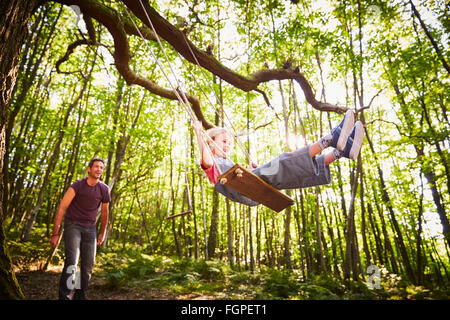Padre figlia di spinta sulla corda swing in foresta Foto Stock