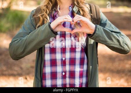 Blonde escursionista framing cuore con le mani Foto Stock