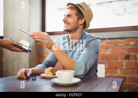 Bello hipster pagando con lo smartphone Foto Stock