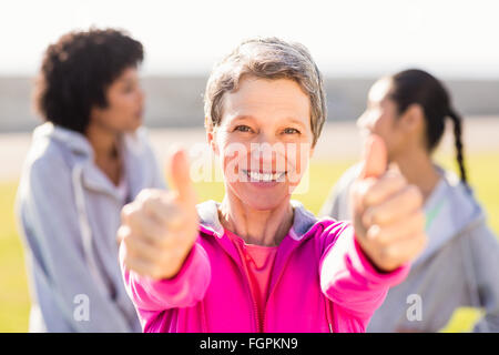 Donna sportivo facendo pollice in alto nella parte anteriore di amici Foto Stock