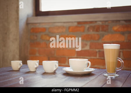 Diverse bevande calde in fila su di un tavolo di legno Foto Stock