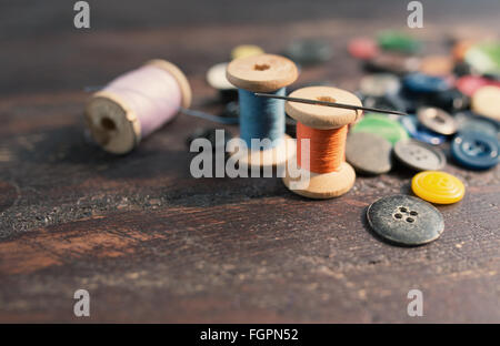 Rocchetti di fili e pulsanti sul vecchio tavolo in legno Foto Stock