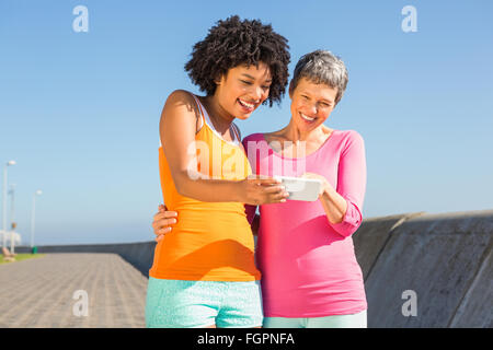 Due sorridenti donne sportive guardando loro selfies Foto Stock