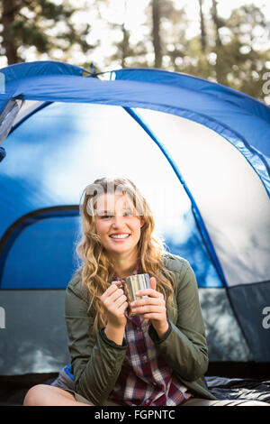 Bella bionda camper sorridente e seduta in tenda Foto Stock