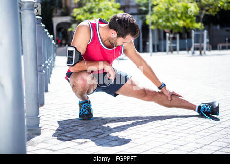 Bello atleta facendo stretching gamba sul pavimento Foto Stock