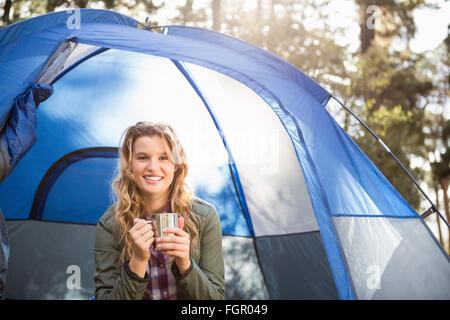 Bella bionda camper sorridente e seduta in tenda Foto Stock
