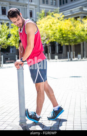 Bello atleta gamba facendo stretching su una quota di partecipazione Foto Stock