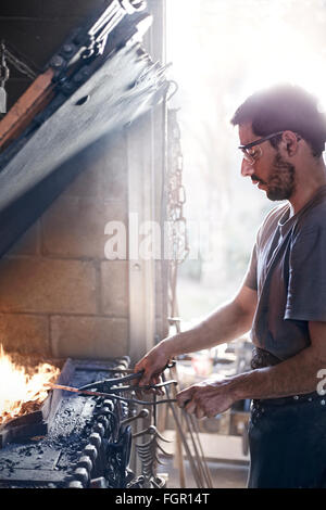 Fabbro lavora sul fuoco nel forge Foto Stock