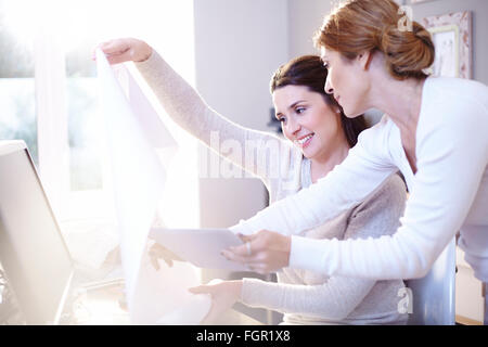 Interior designer con tavoletta digitale discutendo blueprint in office Foto Stock