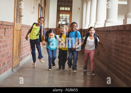 Felice gli alunni tenendo le mani e acceso al corridoio Foto Stock