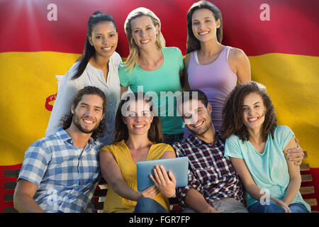 Immagine composita di sorridere amici nel parco utilizzando tablet pc Foto Stock