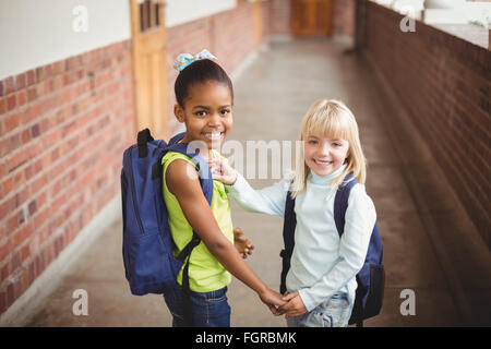 Sorridendo gli alunni tenendo le mani sul corridoio Foto Stock