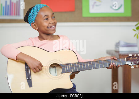 Pupilla sorridente a suonare la chitarra in una classe Foto Stock