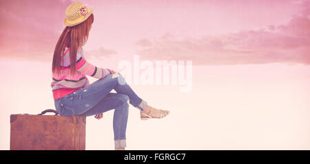 Immagine composita del hipster donna seduta sulla sua valigia Foto Stock