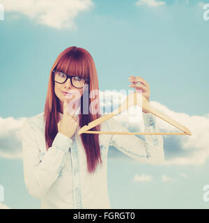Immagine composita di sorridere hipster donna tenendo un appendiabiti Foto Stock