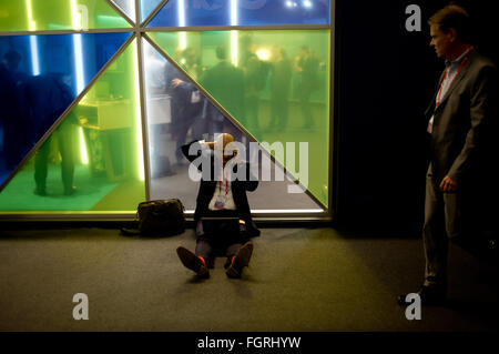 Barcellona, in Catalogna, Spagna. Il 22 febbraio, 2016. Un uomo lavora sul suo computer portatile mentre si parla al telefono al MWC di Barcellona. Inizia di MWC, il mondo è più grande fiera del mobile in cui riunisce le principali società di telefonia mobile e in cui gli sviluppi più recenti nel settore vengono presentati. © Jordi Boixareu/ZUMA filo/Alamy Live News Foto Stock